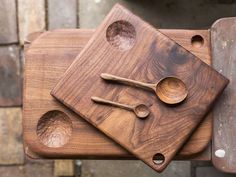 three wooden bowls and spoons sitting on top of a cutting board next to each other