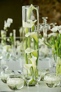 there is a tall vase with flowers in it and several wine glasses on the table