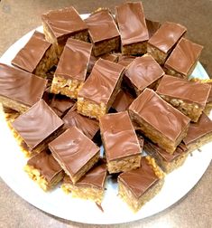 a white plate topped with lots of chocolate covered squares on top of each other,