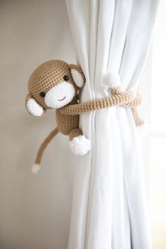 a stuffed monkey hanging from the side of a curtain