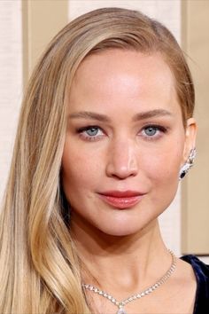 a woman with long blonde hair and blue eyes wearing a diamond choker, necklace and earrings