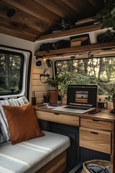 a laptop computer sitting on top of a wooden desk next to a window filled with plants