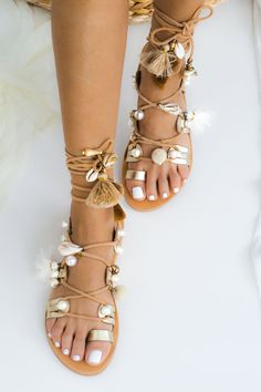 a woman's feet wearing sandals with pearls and tassels