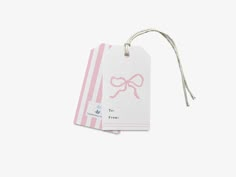 a pink and white striped gift tag with a bow on the front, attached to a string