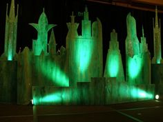 some green lights are shining on the walls and pillars in front of a stage set