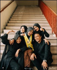 a group of people standing next to each other in front of stairs with their thumbs up