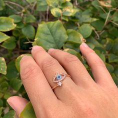 a woman's hand holding an engagement ring with blue and white diamonds on it