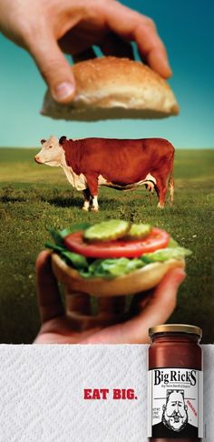 a person holding a sandwich in their hand and a cow standing on the other side