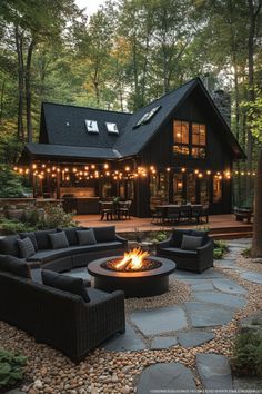 an outdoor fire pit in the middle of a patio with seating and lights around it