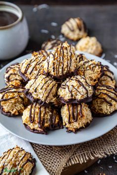 chocolate covered cookies on a white plate next to a cup of coffee