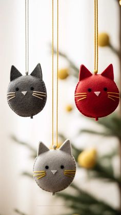 three felt ornaments with cats on them hanging from the ceiling next to a christmas tree