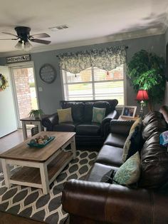 a living room with couches, coffee table and ceiling fan in the middle of it