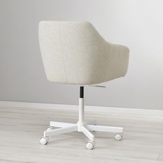 an office chair with casteors and wheels on a white wooden floor in front of a gray wall