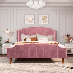 a bed with pink velvet headboard and foot board in a white room, surrounded by pictures on the wall