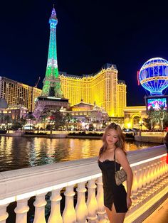 a beautiful young woman standing next to the eiffel tower