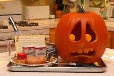 a carved pumpkin sitting on top of a kitchen counter next to an egg carton