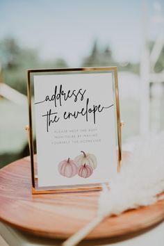 a sign that says address the envelope on top of a wooden table with white feathers