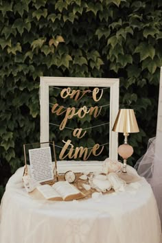 a white table topped with a sign next to a lamp