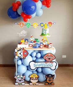 a table topped with balloons and toys on top of a wooden floor next to a wall