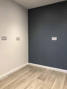 an empty room with wood flooring and two white wall plaques on the gray wall