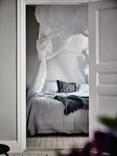 an open door leading to a bedroom with a white canopy over the headboard and bed