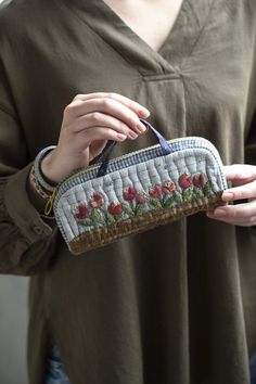 a woman is holding an embroidered purse with flowers on it and the bottom half of her purse