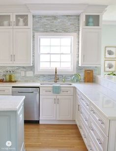 a large kitchen with white cabinets and wood flooring is pictured in this image, there are two chandeliers hanging from the ceiling