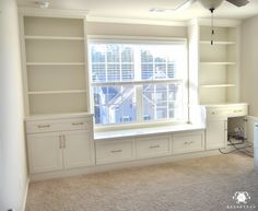 an empty living room with built in bookshelves