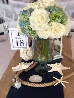 a centerpiece with flowers and seashells is displayed on a table at an event