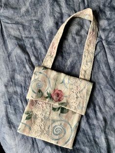 a handbag with a flower on it laying on a blue cloth covered tablecloth