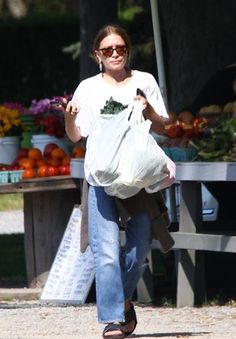 a woman walking down the street carrying a grocery bag