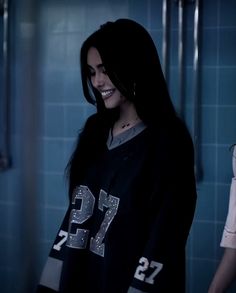 a woman with long black hair standing in a bathroom