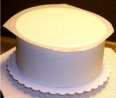 a white cake with scalloped edges on a tableclothed place mat, ready to be cut