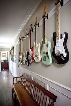 a long hallway with guitars hanging on the wall and a bench in front of it