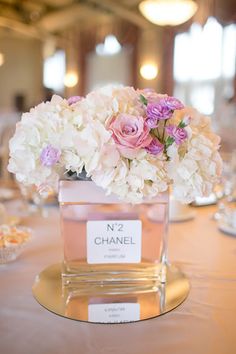 there is a vase with flowers in it on top of a table at a wedding