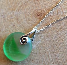 This smaller sized, genuine green and clear sea glass Ohajiki game piece dangles from an 18 inch sterling silver chain from a charming sterling silver swirl bail. Can be worn with either side facing out for two different looks, as shown! A dime(not included) is shown to demonstrate size. Great gift for yourself or your favorite beachcomber or sea glass collector. Thanks for Looking! Nickel-free Round Recycled Glass Jewelry, Green Recycled Glass Jewelry For Healing, Green Recycled Glass Pendant Jewelry, Healing Green Jewelry From Recycled Glass, Healing Green Recycled Glass Jewelry, Green Sea Glass Necklaces For Jewelry Making, Green Sea Glass Necklace For Jewelry Making, Green Round Nickel-free Necklace, Sea Glass Round Necklace As Gift