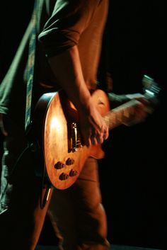 a man playing an electric guitar in the dark