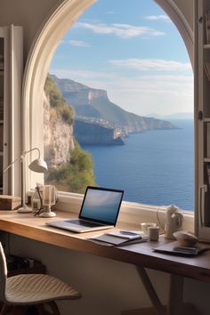 an open laptop computer sitting on top of a wooden desk next to a large window