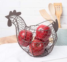 a wire basket filled with apples sitting on top of a table next to utensils