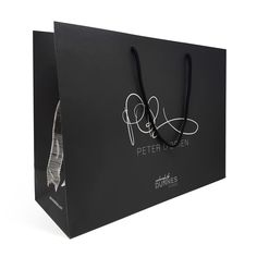 a black paper bag with white writing on the front and side, tied to it