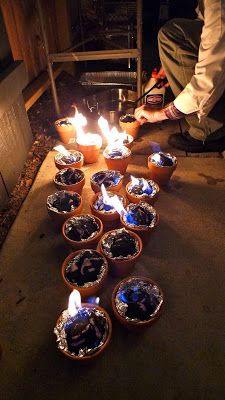 there are many small pots with candles in them on the ground and one person is lighting something