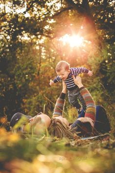 a woman holding a small child up in the air while laying on top of her