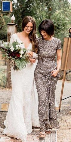 two women standing next to each other in front of an easel with flowers on it