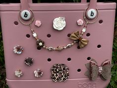 a pink purse with lots of different types of buttons and bows attached to it's handles