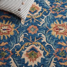 a blue and white rug with an ornate design on the bottom, along with a striped pillow