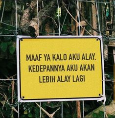 a yellow sign that is on the side of a fence with trees in the background