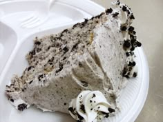 a white plate topped with a piece of cake covered in oreo cookies and cream