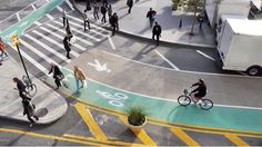 an aerial view of people walking and riding bikes on a city street in the daytime