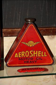 a red and yellow sign sitting on top of a glass shelf next to a bottle