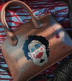 a handbag with a painted image of a clown on the front and side of it